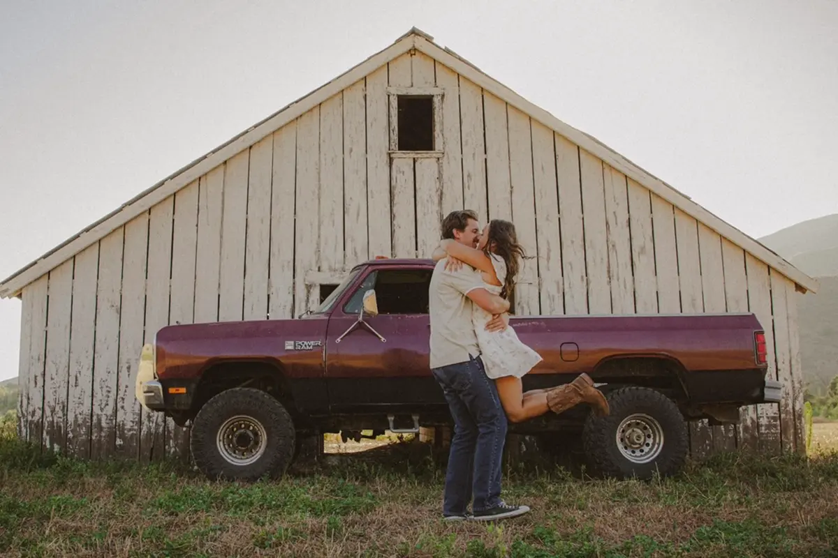 man hold woman up standing in front of truck