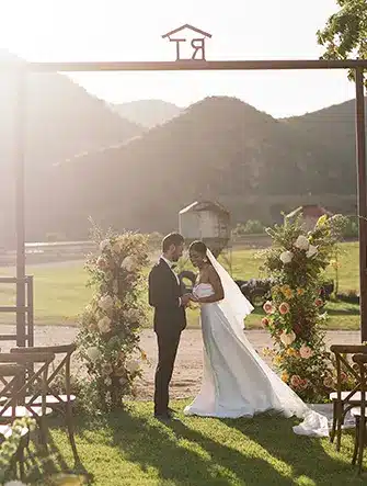 Bride and Groom sanding in front of an arch